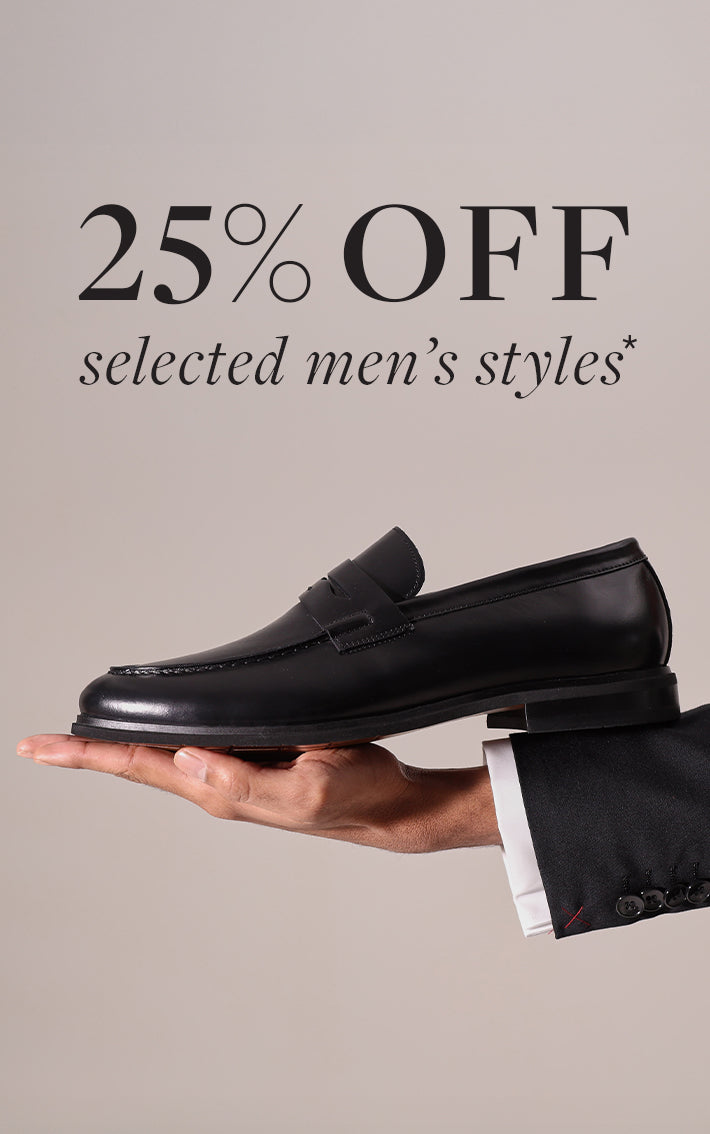 Black loafer shoe held in a hand with promotional text '25% OFF selected men's styles' on a beige background
